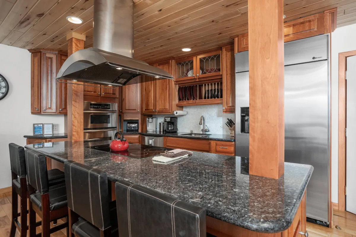 A granite countertop kitchen with stainless steel appliances, beautiful wood cabinetry, and a kitchen island with seating. The layout encourages both meal preparation and casual dining, making the kitchen a true gathering place for cooking or entertaining.