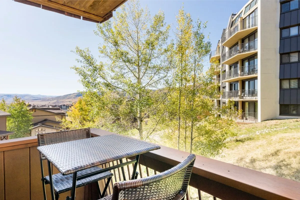 A peaceful outdoor seating area overlooking trees and distant hills, bathed in warm sunset light. The balcony setting invites relaxation and offers a vantage point for enjoying the changing seasons and natural beauty surrounding the property.